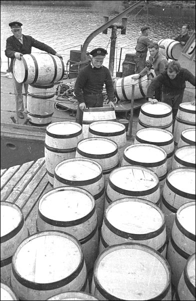 Fishermen loading barrels of oil