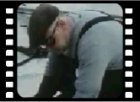 Still from montage of men at work on the QE2.